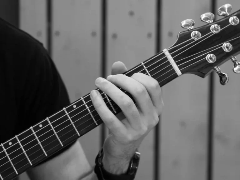 Main du luthier FP Guitars tenant le manche d’une guitare artisanale finie