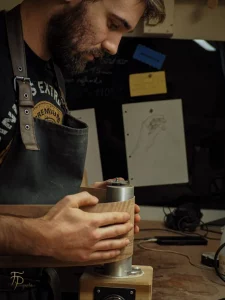 Florian Perronnet, luthier FP Guitars, en train de cintrer une éclisse en noyer sur un fer à cintrer dans son atelier en Haute-Savoie.