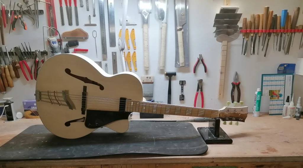 Guitare archtop FP Guitars posée sur l’établi du luthier. tarifs luthier FP Guitars